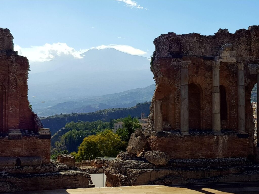 Ancient Taormina theatre ruins with Mount Etna rising in the background