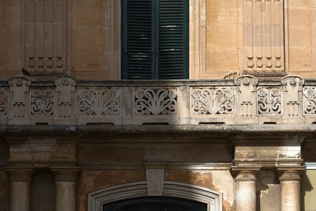 Détail de balcon sculpté en pierre avec volets verts, Sicile