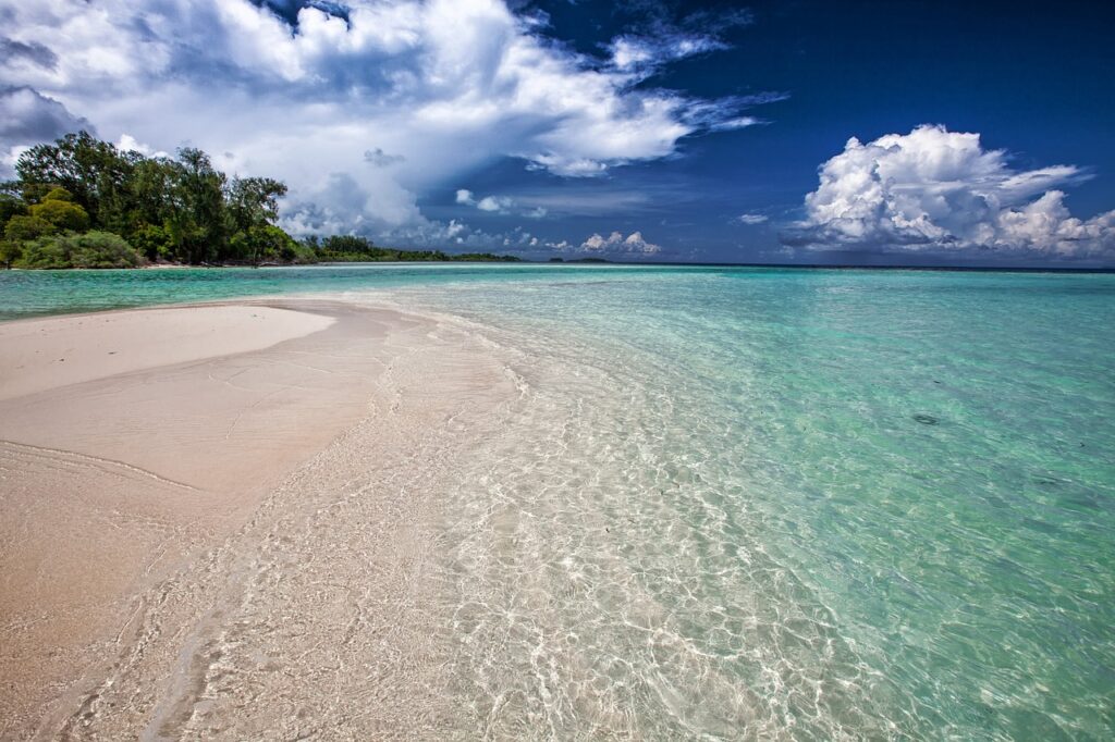 Plage de sable blanc et eau turquoise translucide sous nuages dramatiques en Sicile