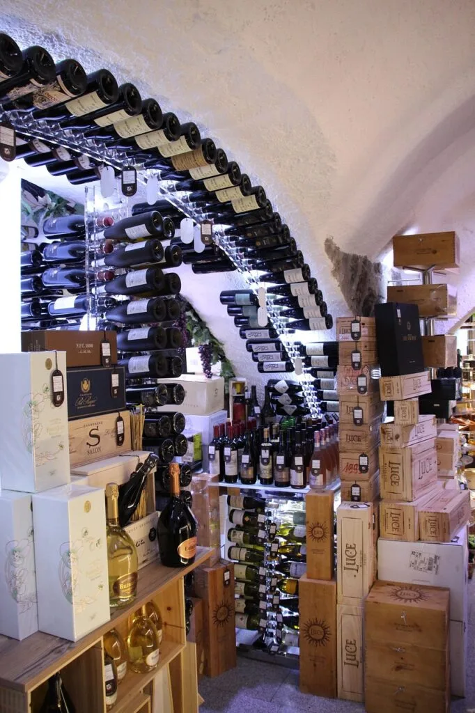 Enoteca con scaffali di bottiglie e casse impilate sotto arco in Sicilia