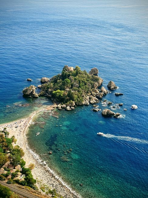 Petite île rocheuse reliée à la côte par un tombolo, eaux bleu profond en Sicile
