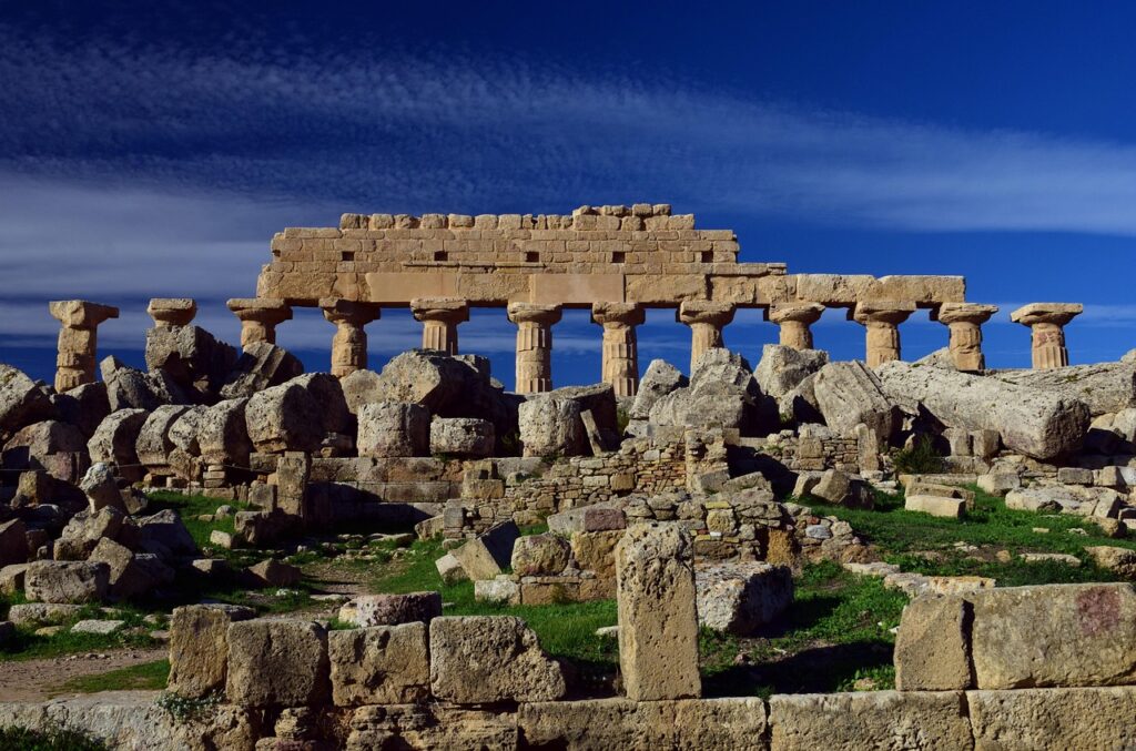 Ruins of Selinunte archaeological site with collapsed Doric columns under deep blue sky