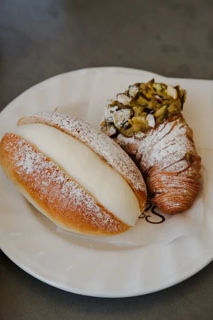 Assiette de pâtisseries siciliennes : brioche à la crème et cannoli pistache