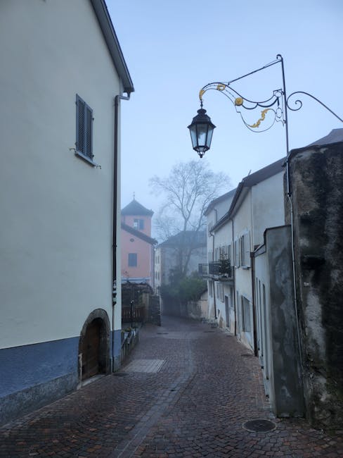 Ruelle pavée brumeuse d'un village au bord du Lac Majeur, lampadaire ancien