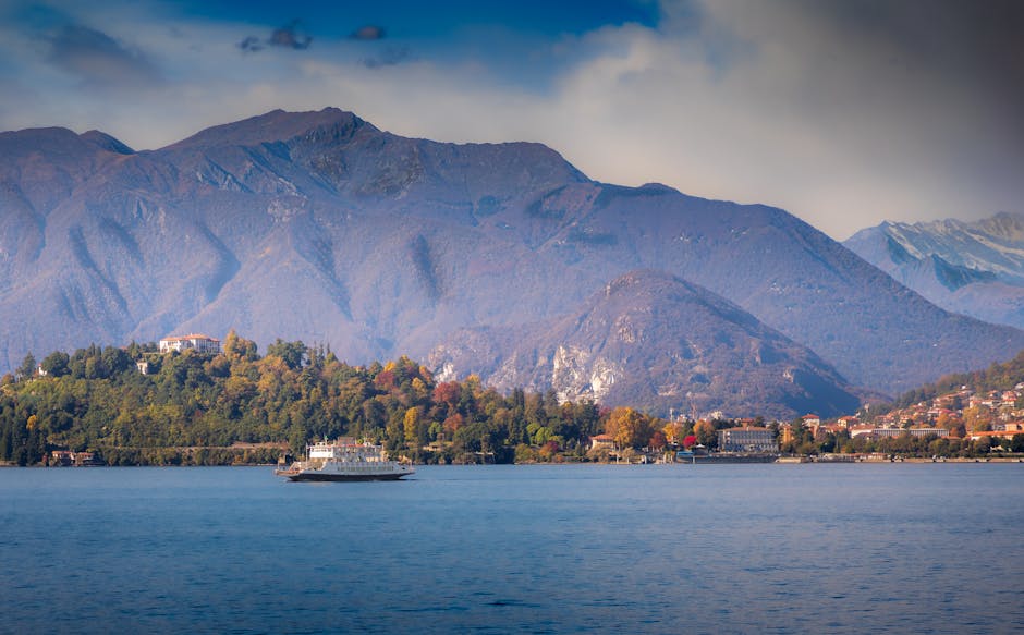 Car ferry crossing calm waters of Lake Maggiore with mountain backdrop