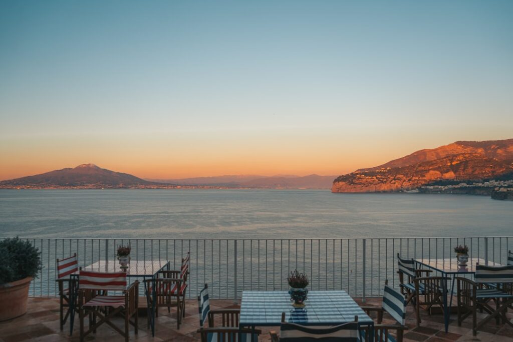 Striped chairs and tables on terrace overlooking Lac Majeur at sunset