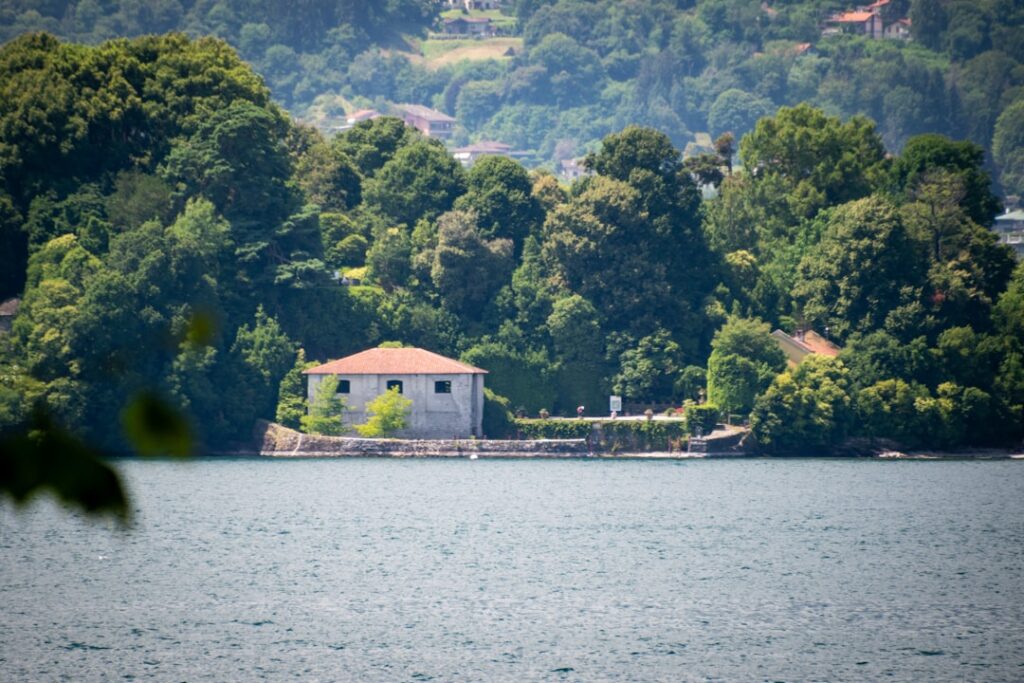 Small stucco boathouse nestled among trees on Lac Majeur shoreline
