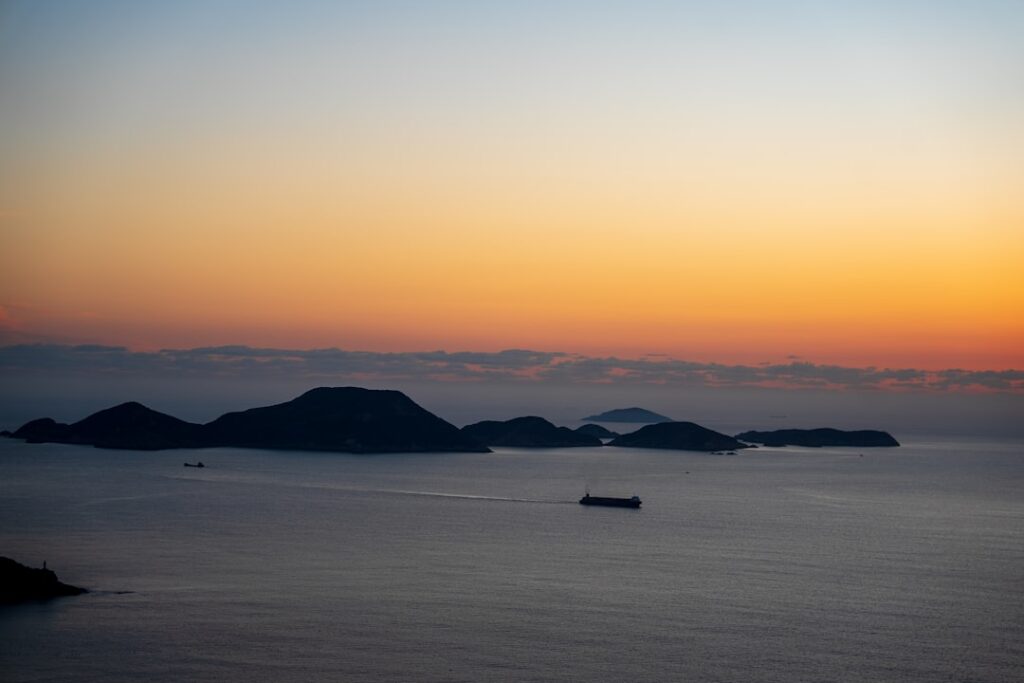 Ochtendgloed boven silhouetten van eilanden met een schip op zee