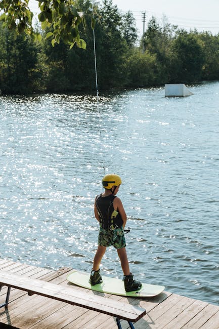 Kind mit gelbem Helm auf Steg bereit zum Wakeboarden