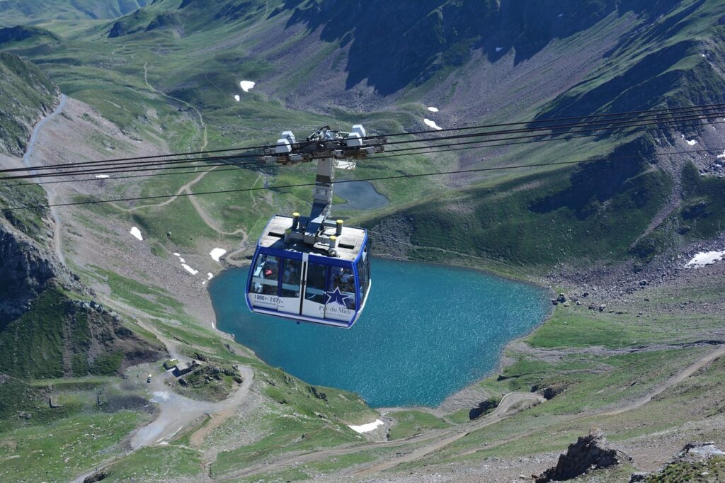 Télécabine au-dessus d'un lac de montagne turquoise et de pentes herbeuses