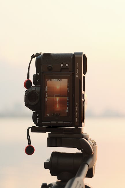 Fotouitrusting op statief bij het meer tijdens zonsondergang
