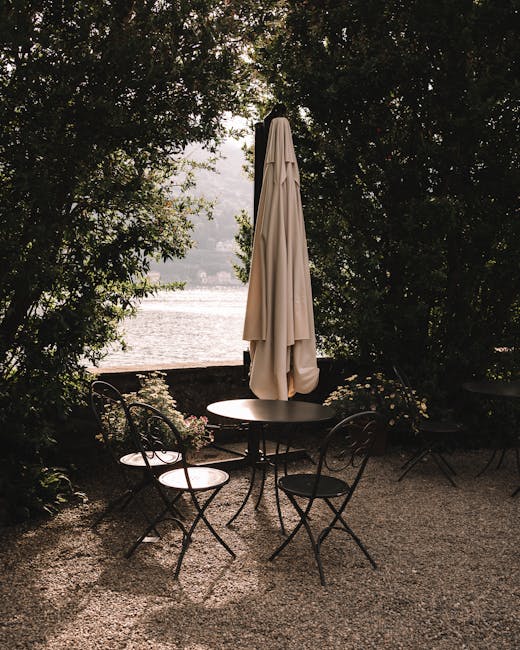 Leerer Gartentisch mit geschlossener Sonnenschirm, Blick auf Lago Maggiore