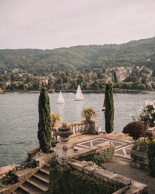 Terras met stenen balustrade en zeilboten op Lago Maggiore