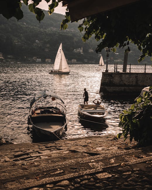 Zwei Boote am Ufer, Segelboot auf dem Lac Majeur im Abendlicht