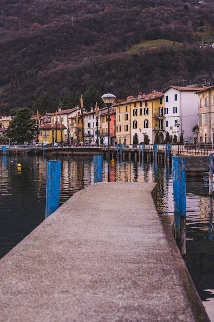 Concrete jetty pointed toward colorful waterfront buildings along Lac Majeur