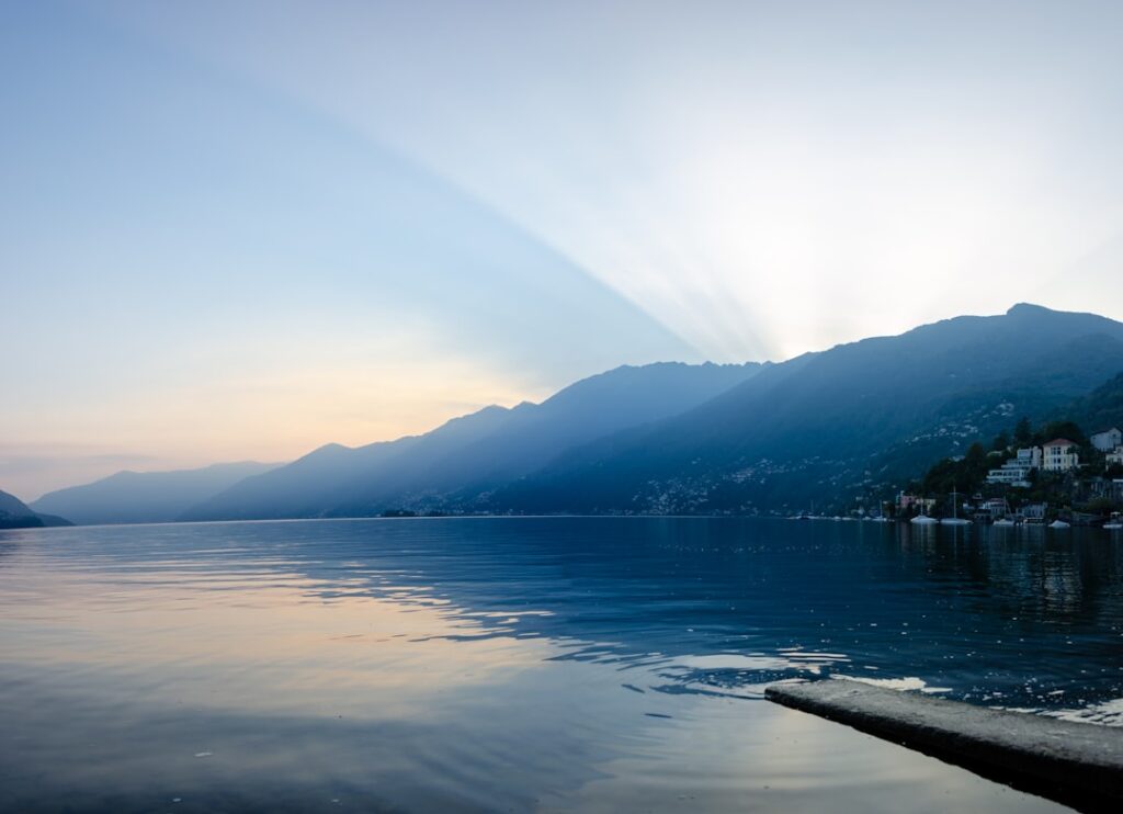Sun rays fanning over mountains as dawn reflects across Lac Majeur