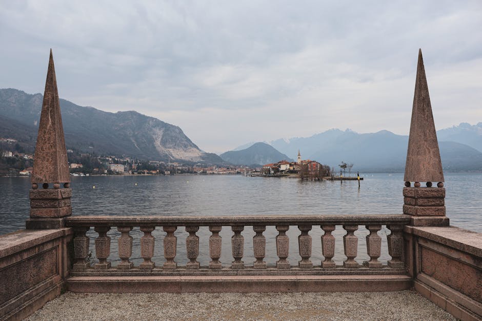 Stone balustrade framing a small island on Lac Majeur against mountains