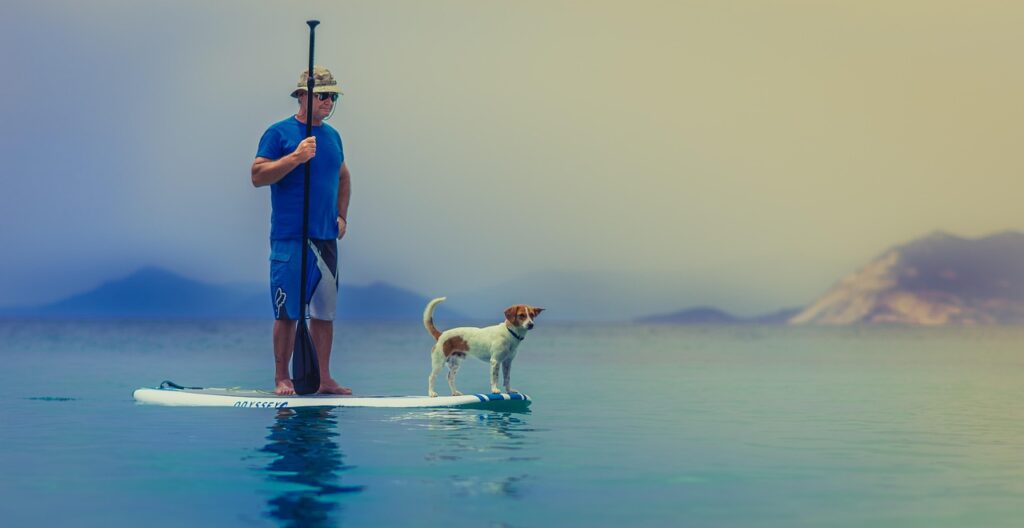 Uomo con cane su SUP, equilibrio calmo sulle acque del Lago Maggiore
