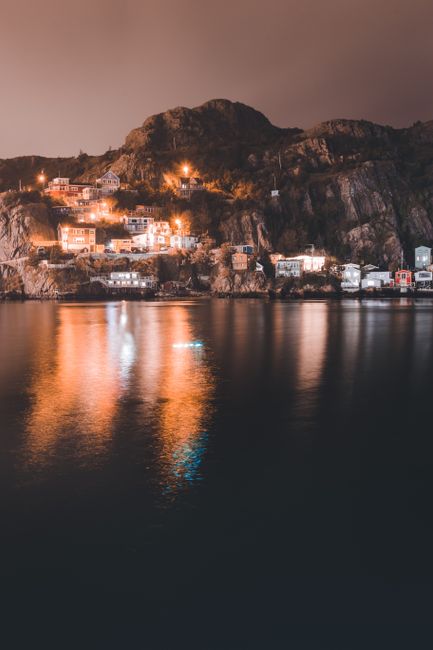 Cliffside houses lit at night, warm reflections on Lake Maggiore