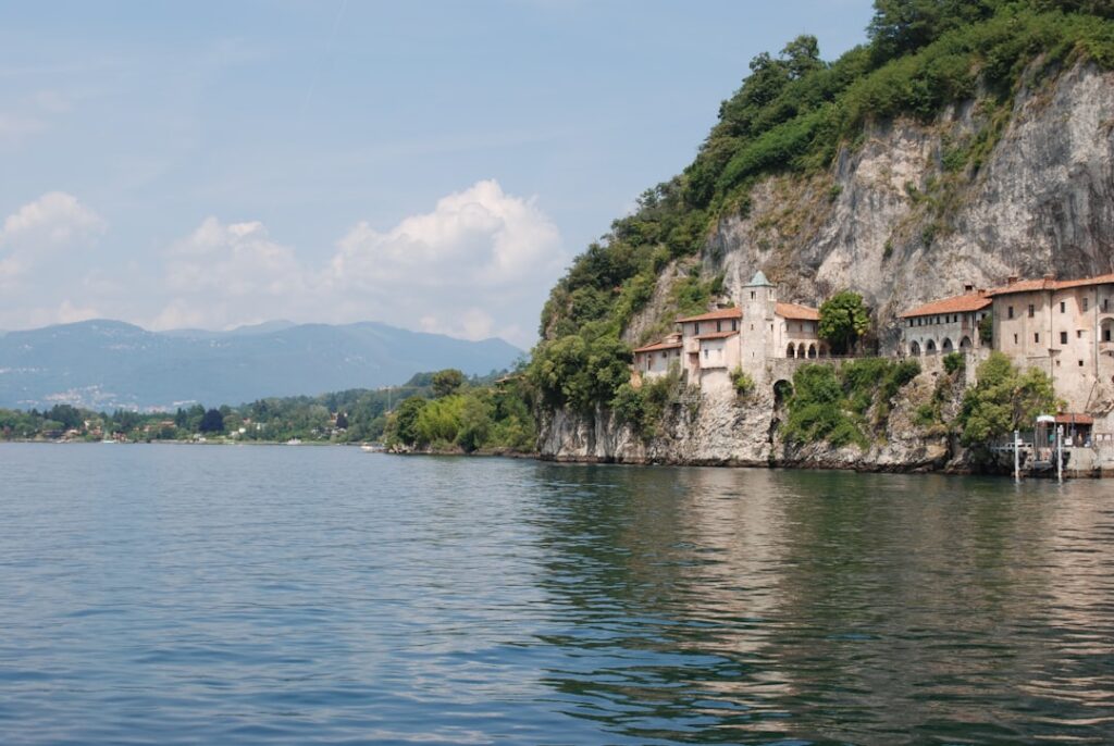 Medieval houses clinging to rocky cliffs above Lac Majeur's shimmering water