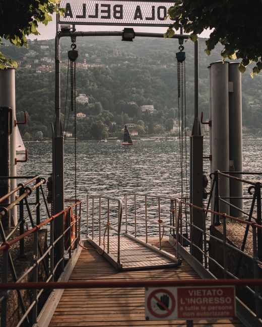 Pontile con passerella e cartello, vista sul Lago Maggiore e vela