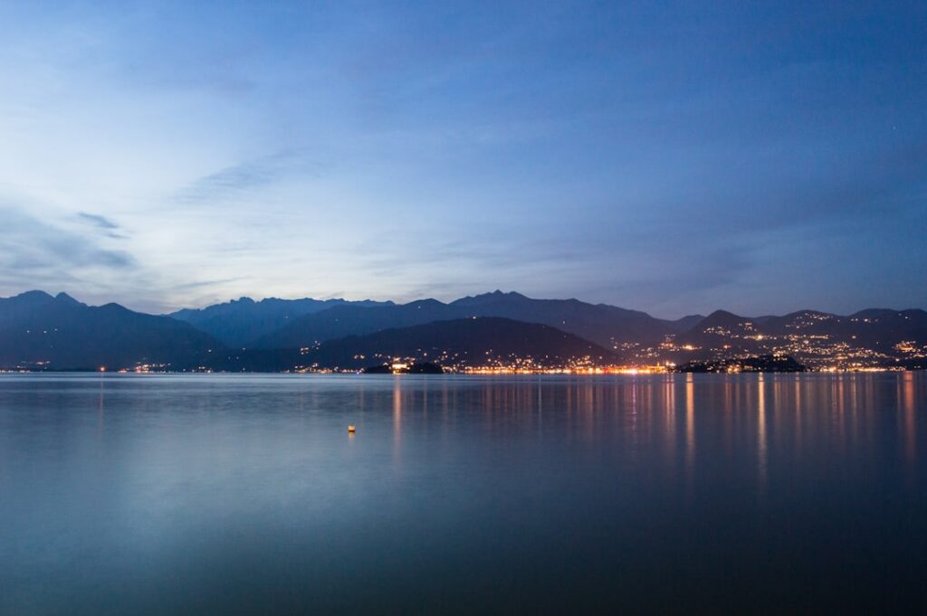 Twilight over Lac Majeur with distant town lights reflecting on calm water