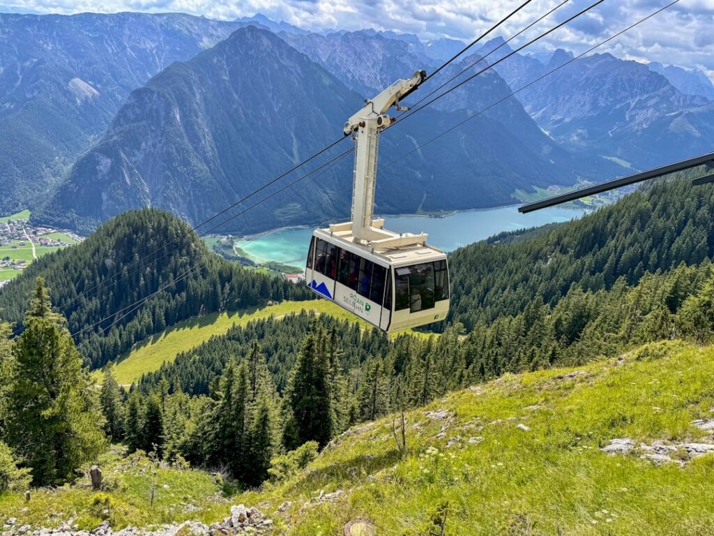 Télécabine descendant au-dessus d'une vallée montagneuse, lac visible en contrebas