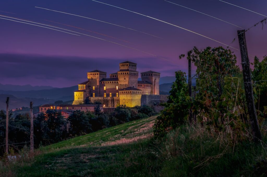 Beleuchtete Burg bei Nacht mit Weinberg im Vordergrund in Ombrien