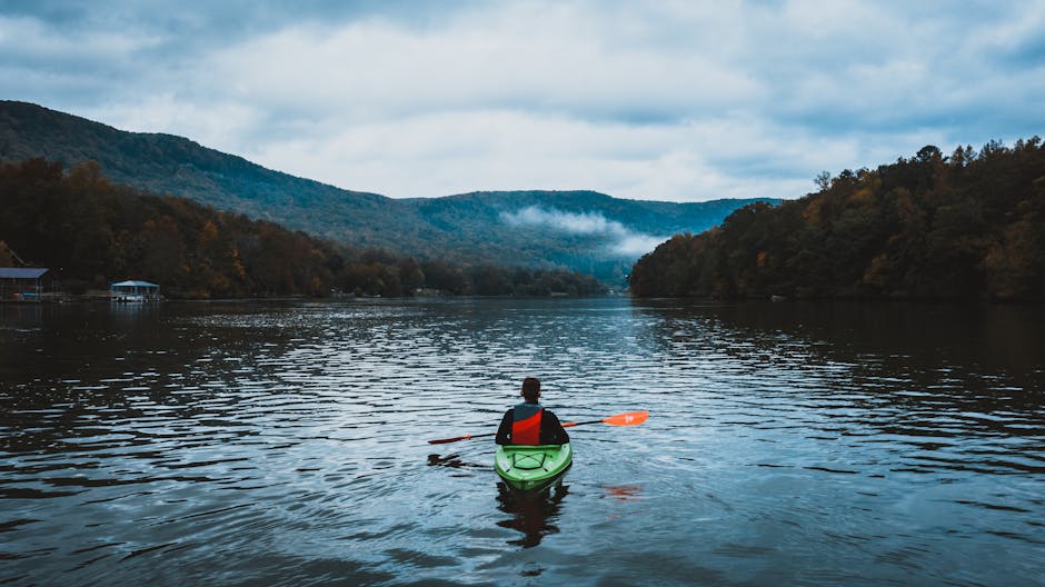 Canoista in kayak verde pagaia verso la nebbia sul Trasimeno, Umbria