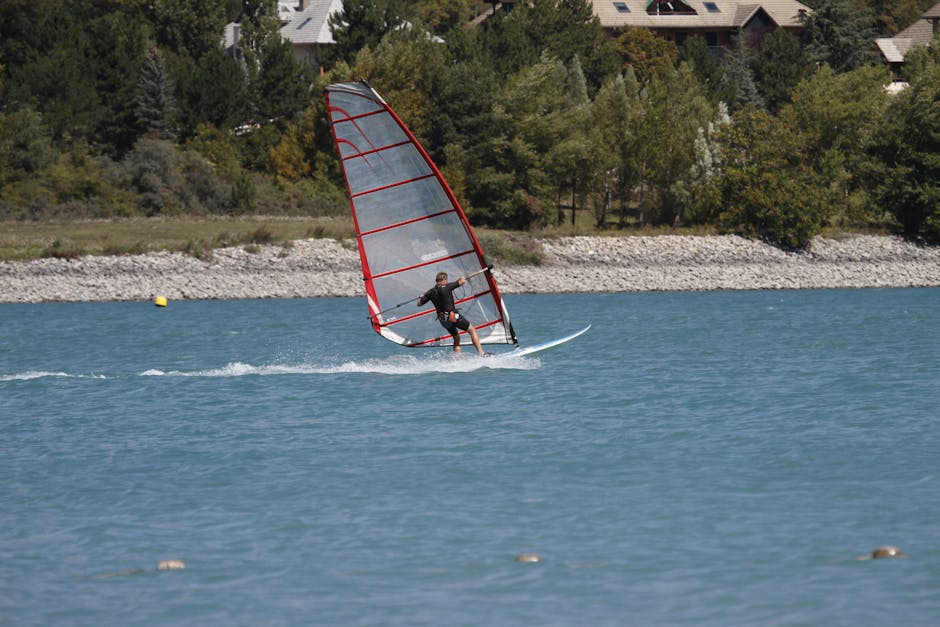 Windsurfista con vela rossa scivola sull'acqua del Lago Trasimeno