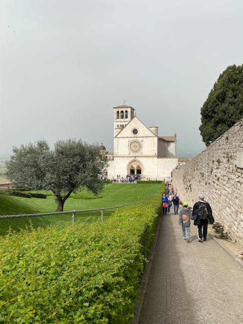 Visitors walking toward Basilica of Saint Francis across lush Assisi lawn