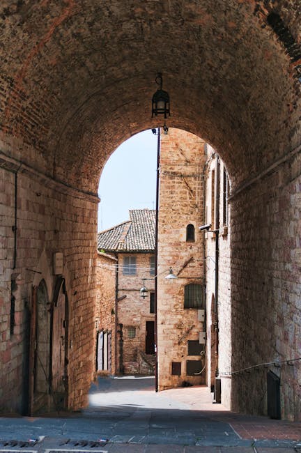 Arched stone gateway framing a narrow medieval street in Assisi