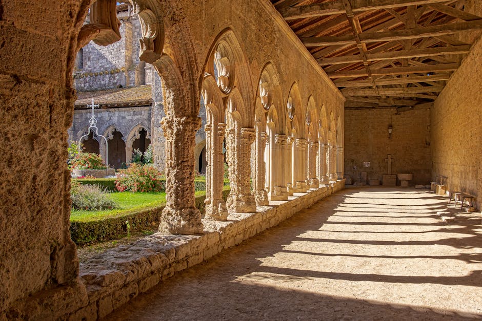 Sunlit medieval cloister arcade with garden at Sacro Convento, Assisi