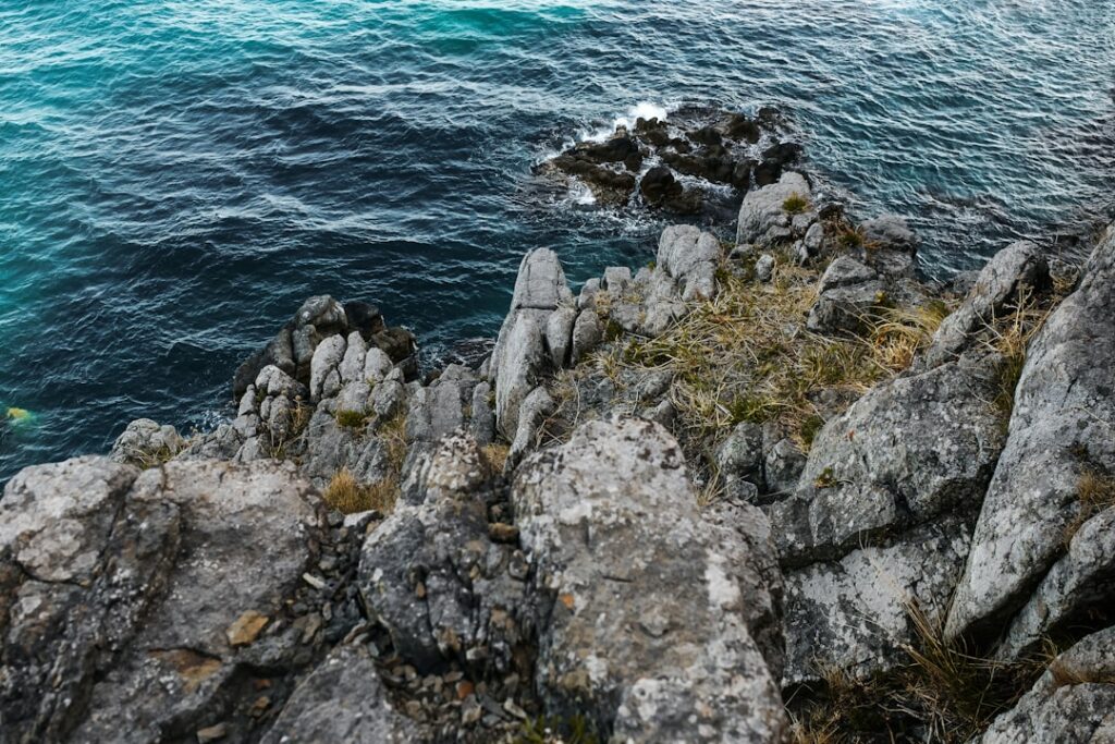 Primo piano di rocce frastagliate a picco su acqua turchese