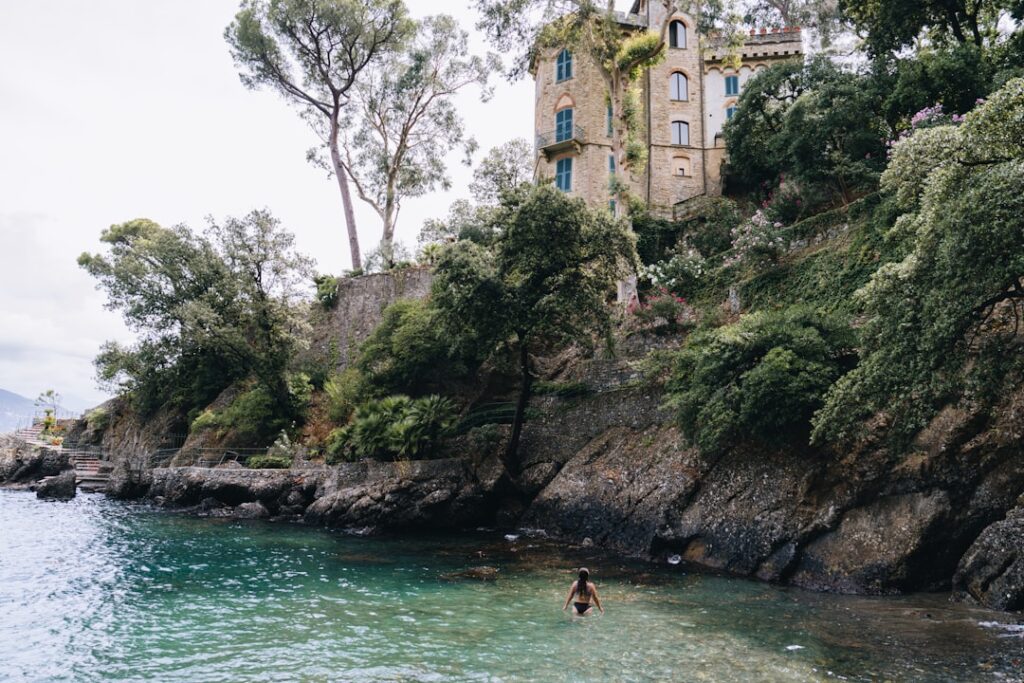 Donna che entra nell'acqua vicino a scogliera e villa panoramica