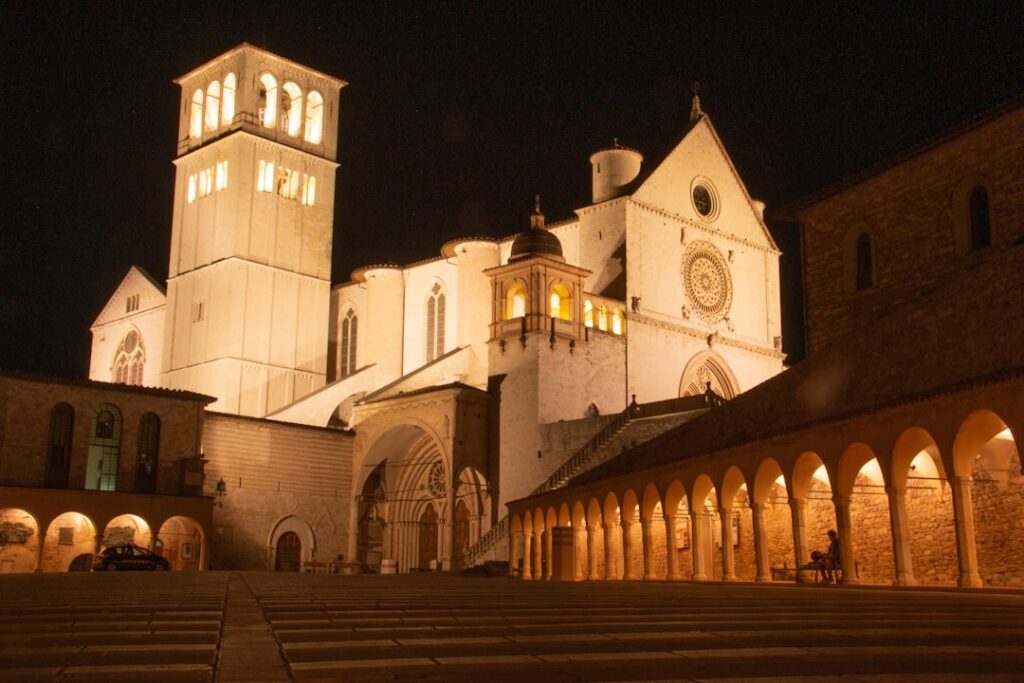 Illuminated Basilica of Saint Francis and cloister arches in Assisi at night