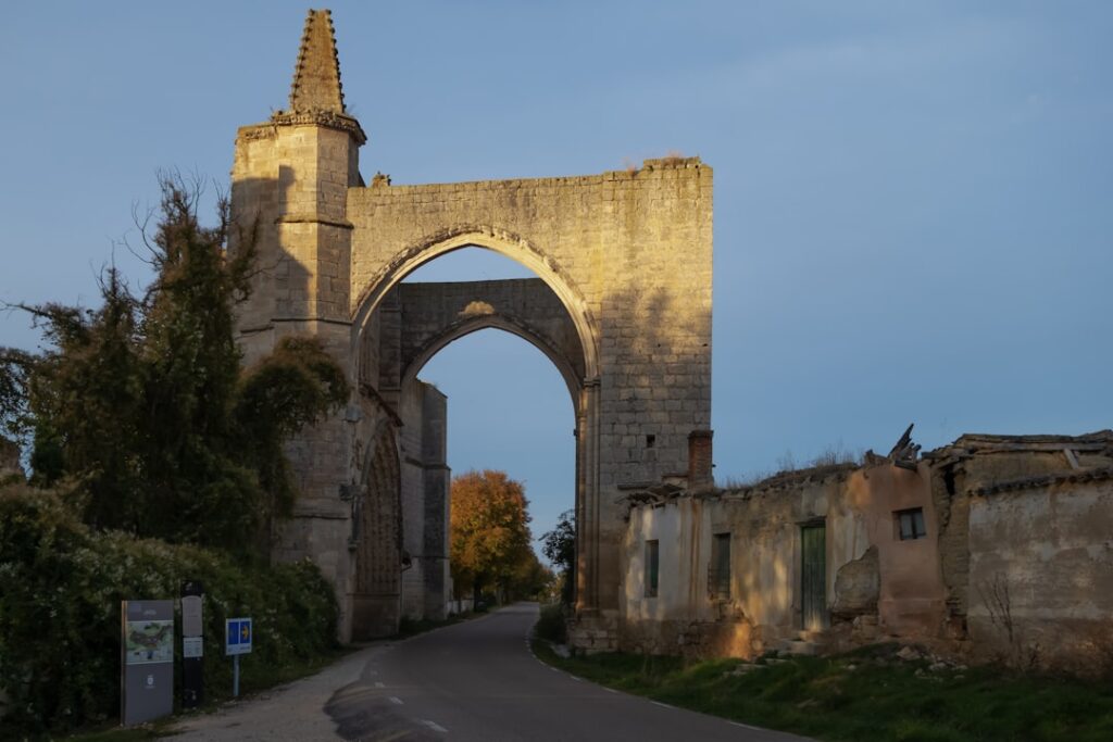 Sunlit medieval stone archway ruins spanning country road in Umbria
