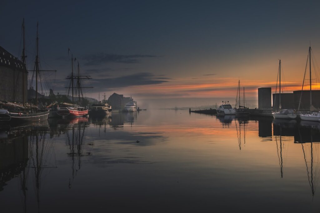 Port au crépuscule avec voiliers et reflets sur l'eau, Ombrie