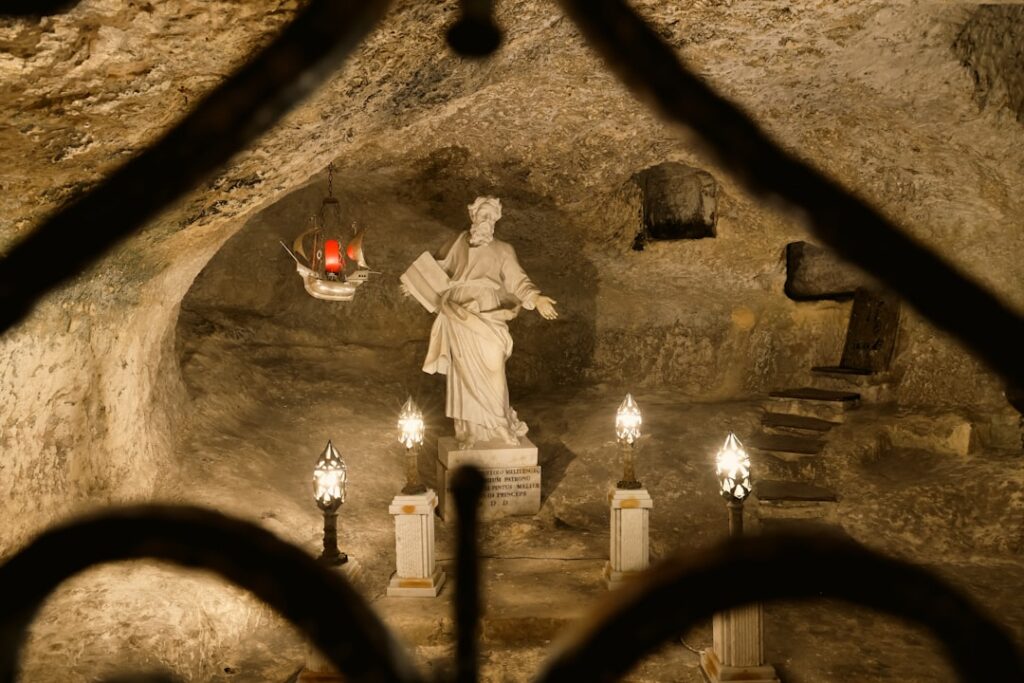 Marble statue in subterranean crypt beneath Assisi basilica, lit by lamps