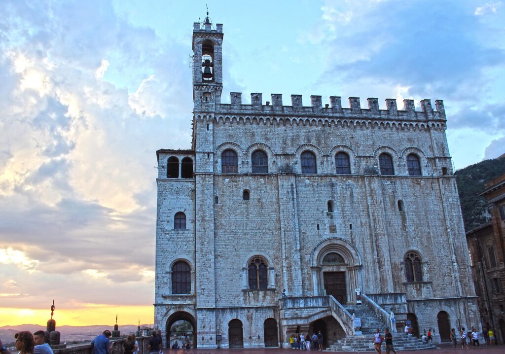 Palazzo dei Consoli a Gubbio, Umbria, con torre campanaria e cielo al tramonto