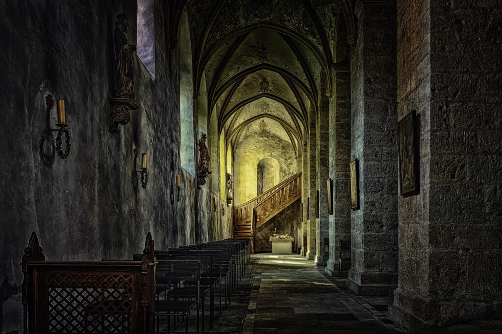 Nef latérale sombre du monastère d'Assise aux arches gothiques.