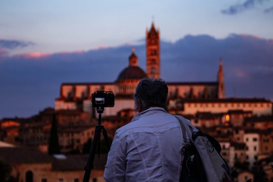 Photographe au crépuscule face au panorama, cathédrale ombrienne floue au loin