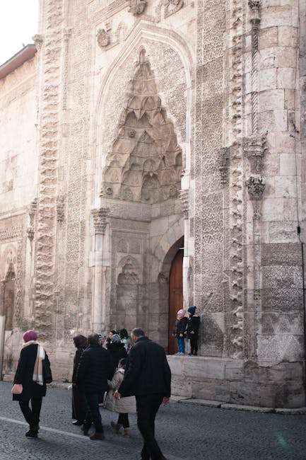 Portail richement sculpté d'une église ombrienne, passants au premier plan