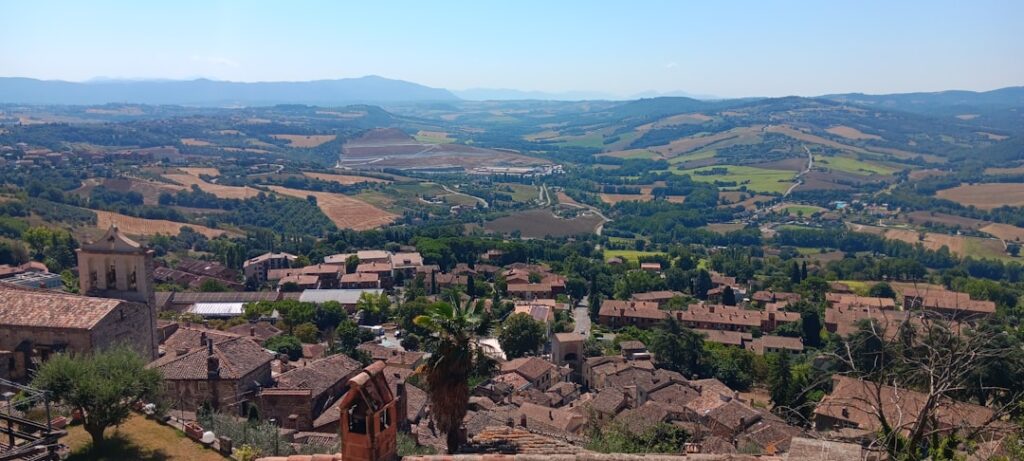 Panorama sulla valle umbra con colline ondulate e tetti del borgo