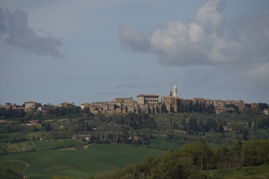 Borgo murato su collina circondato da campagna e cipressi