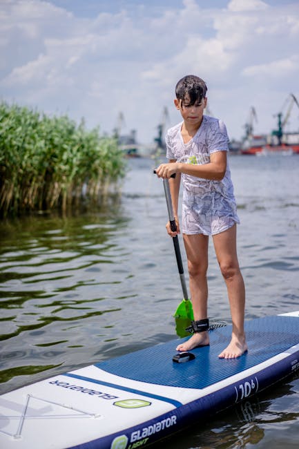 Chłopiec na desce SUP pływa przy trzcinach na jeziorze Trasimeno