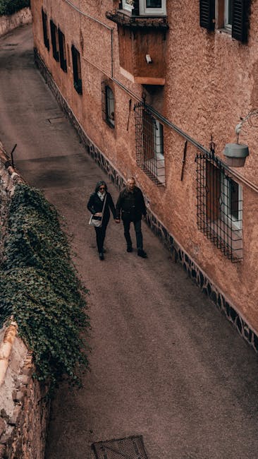 Coppia che passeggia per un vicolo di borgo italiano tenendosi per mano