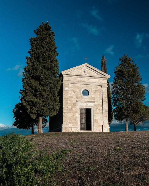 Filare di cipressi nella campagna umbra verso una cappella