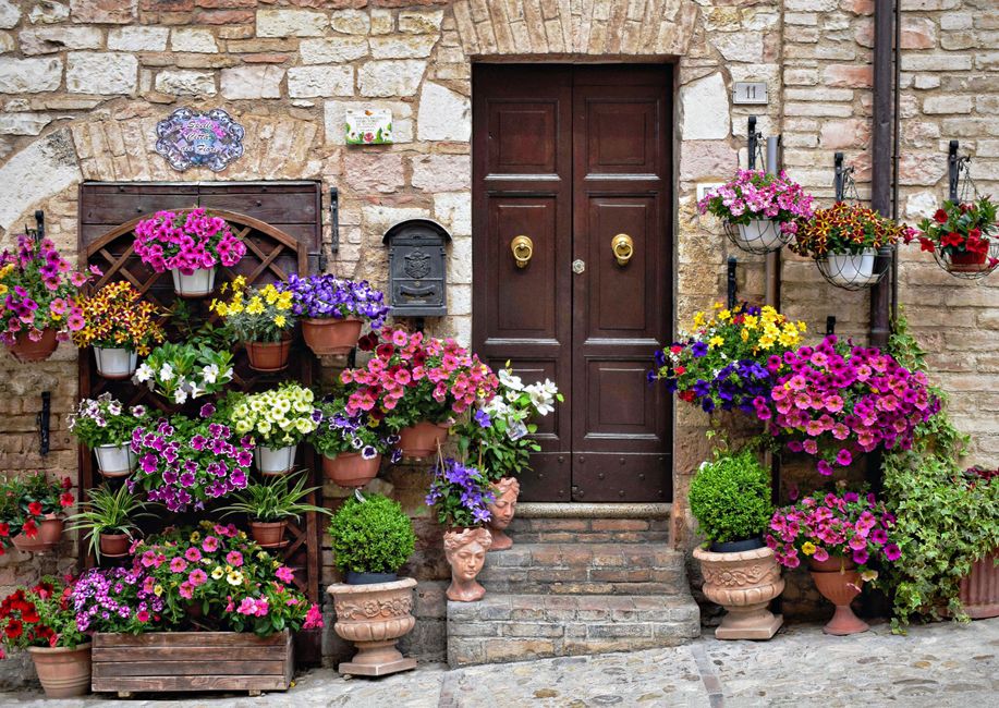 Ingresso fiorito di una casa a Spello, Umbria, con vasi colorati