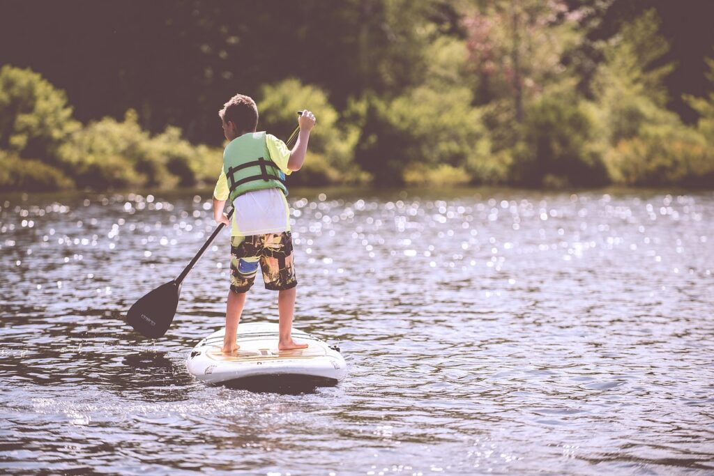 Enfant en gilet pagayant sur un paddle au bord du lac Trasimène